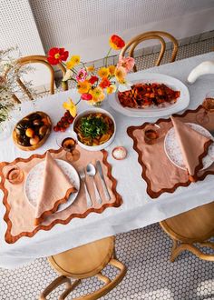 the table is set with plates, bowls and utensils for two people to eat