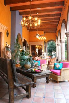 a living room filled with lots of furniture under a chandelier hanging from the ceiling