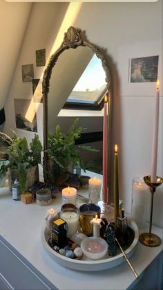 candles and other items on a table in front of a mirror with an arched frame