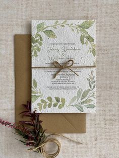 the wedding stationery is decorated with greenery and tied in twine to brown paper