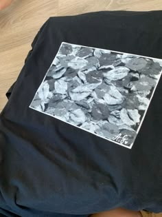 a black t - shirt with white and grey leaves on it