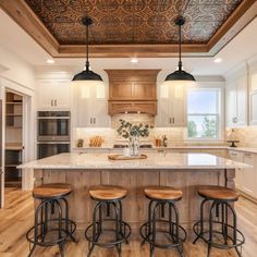 a kitchen with an island and four stools in front of the counter top area