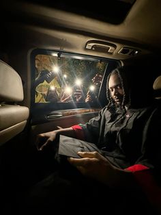 a man sitting in the back seat of a car with his hand on a piece of paper