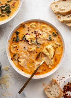 two bowls of soup with bread on the side