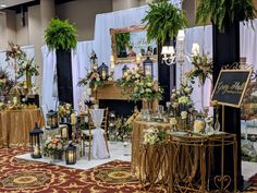 a room filled with lots of tables covered in flowers and greenery next to a fire place