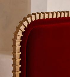 a red velvet chair with wooden slats on the back