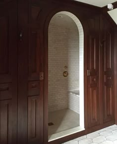 an arched doorway leads into a bathroom with white tile flooring and wood paneling