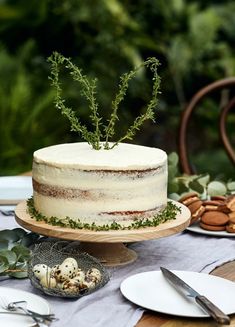 a white cake sitting on top of a table next to plates and utensils