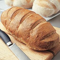 a loaf of bread sitting on top of a wooden cutting board next to a knife