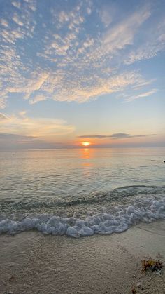 the sun is setting over the water at the beach