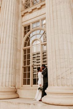 a bride and groom are standing in front of an old building with large columns on either side