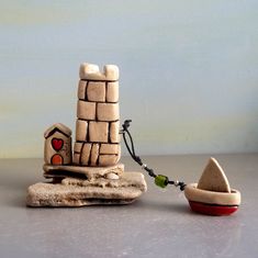 a small toy house on top of a rock next to a red bowl with a green bead