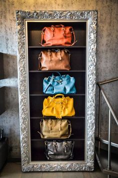 four purses are lined up in a silver frame on the wall next to each other