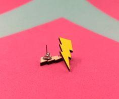 a pair of yellow lightning bolt earrings sitting on top of a pink and blue surface