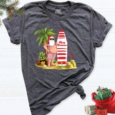 Escape to a tropical Christmas paradise with our "Christmas On The Beach Shirt." Embrace the holiday spirit in a unique way, celebrating Christmas in the warmth of the sun and the soothing sound of the waves. Our Tropical Christmas Shirts capture the essence of a beachside celebration, featuring a jolly Santa lounging under swaying palm trees. The Hawaii Santa Family Matching Tee lets your entire family partake in this festive, relaxed style. These Christmas Palm Tree Tees are the perfect attire Beach Tshirt, Surfing Santa, Christmas Vacation Shirts, Christmas Beach, Hawaiian Christmas, Funny Santa Claus, Class Outfit, Tropical Holiday, Tropical Christmas