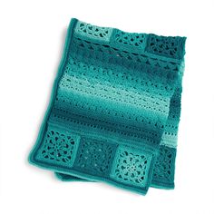 a green crocheted blanket sitting on top of a white surface