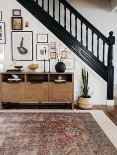 a living room with an area rug, wooden furniture and pictures hanging on the wall