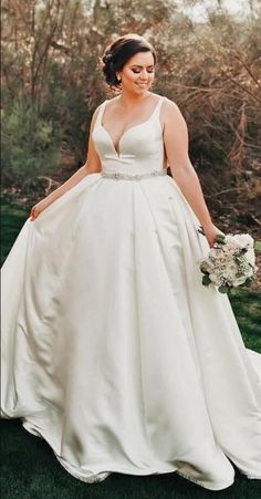 a woman in a wedding dress is walking through the grass