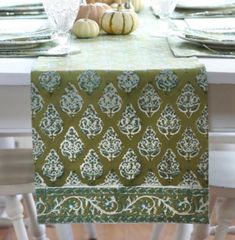 the table is set for thanksgiving dinner with white pumpkins