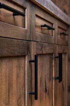 a close up of a wooden cabinet with black handles