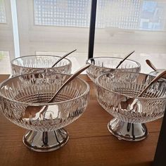 three glass bowls with spoons in them on a table