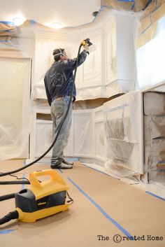 a man is using a vacuum to clean the walls in a room that has been painted white