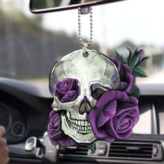 a skull with purple roses hanging from it's side mirror in a car,