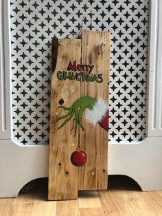 a wooden sign that says merry christmas with an image of the grin face on it