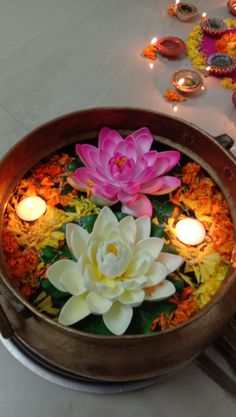 there are candles and flowers in the bowl on the table next to each other,