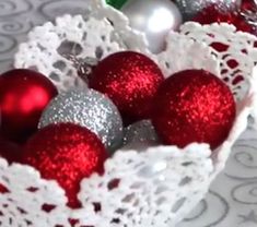 red and silver ornaments in a white lace basket on a tablecloth with crocheted doily