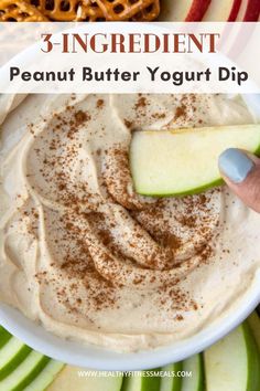 an apple slice being dipped into a bowl of peanut butter yogurt dip