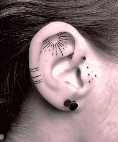 a woman with black dots on her ear has a sun and moon tattoo behind the ear