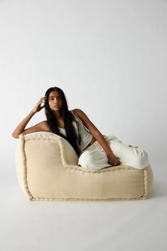 a woman is sitting on a bean bag chair and talking on the phone while holding her hand up to her ear