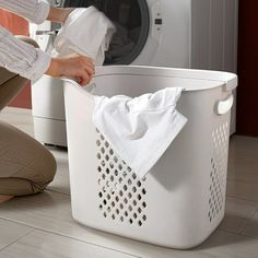 a woman is doing laundry in front of a washing machine