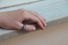 a person's hand resting on the edge of a window sill with their ring