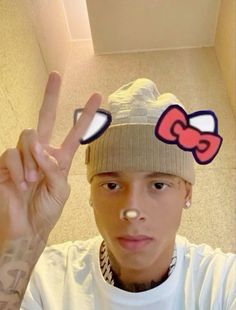 a person with a beanie on their head making the peace sign