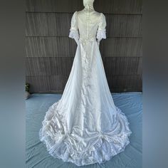 a white wedding dress is on display in front of a wooden wall and blue sheets