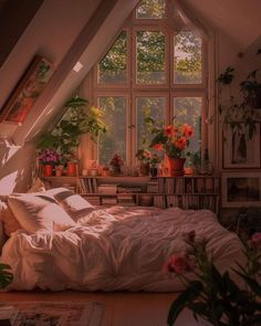 a bed sitting under a window in a bedroom next to a table with flowers on it