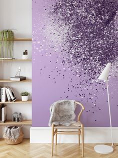 a chair sitting in front of a wall with purple and blue paint splattered on it