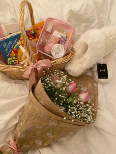 a basket filled with baby's breath and lots of other items sitting on top of a bed