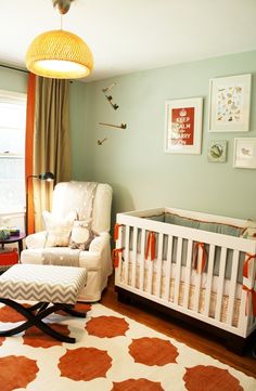 a baby's room is decorated in orange, white and gray colors with an animal print rug on the floor