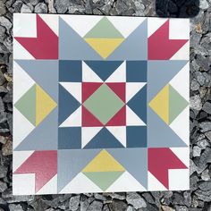 a patchwork quilt on the ground with rocks in the foreground and gravel behind it