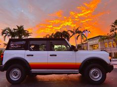 a white truck parked in front of a building with palm trees on the other side