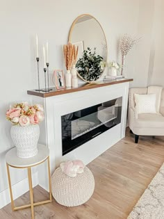 a living room with white furniture and flowers on the fireplace mantel, along with a mirror