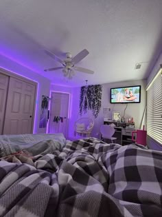 a bedroom with purple lighting and plaid blankets on the bed, television in the corner