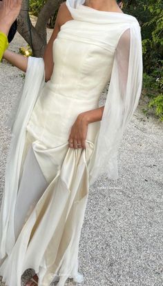 a woman in a white dress and veil posing for the camera with her hand on her hip