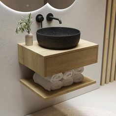 a black bowl sink sitting on top of a wooden shelf next to a wall mounted mirror