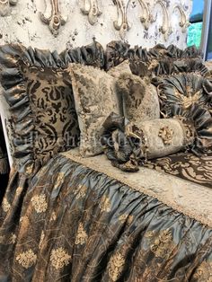 a bed with black and gold comforter, pillows and decorative wall hangings on the headboard