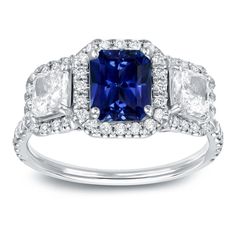 a blue and white diamond ring with three stones on the side, surrounded by diamonds