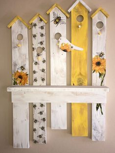 painted wooden birdhouses and bees hang on the wall with sunflowers in them